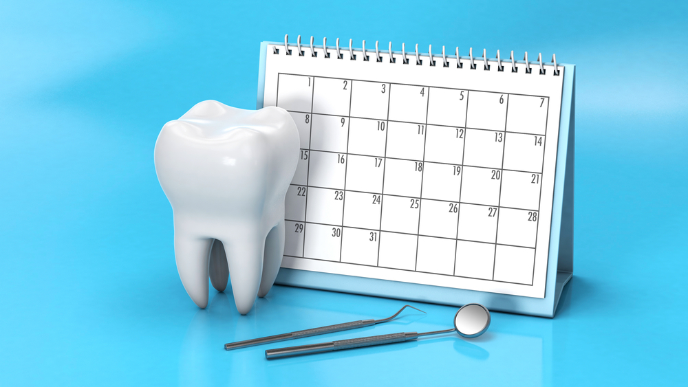 Calendar with a tooth and a dental mirror on a blue background.