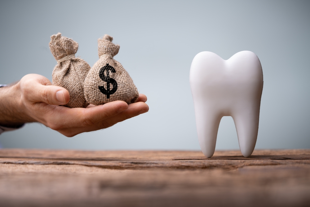 Dental Tooth with hand holding money bags